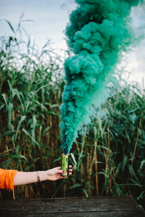 Green smoke bomb in female hand by Karolina Grabowska